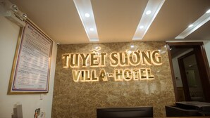 A reception desk with a sign reading "Tuyet Suong Villa-Hotel" and a posted hotel regulation notice.