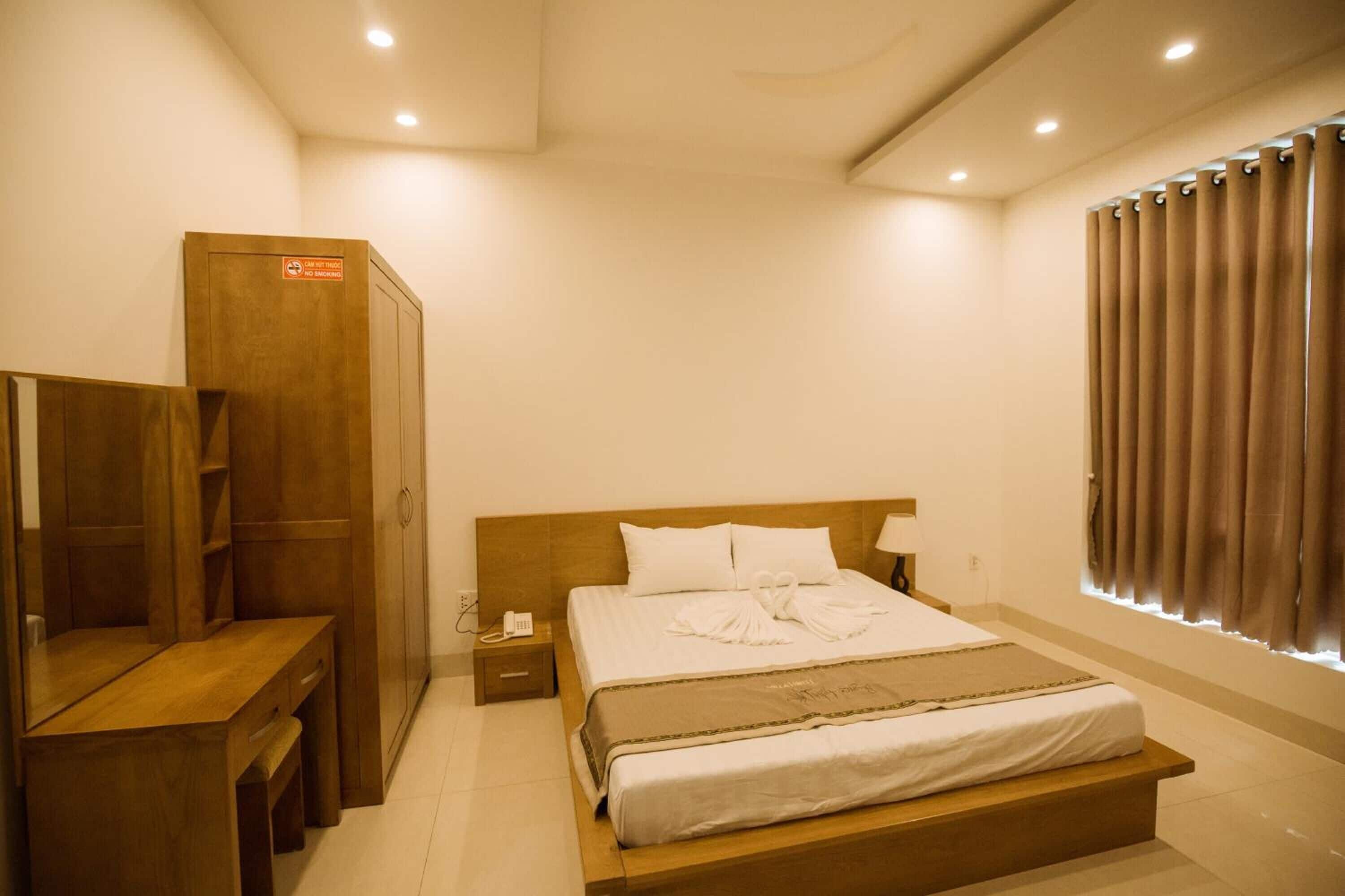 A hotel room with a wooden bed, a desk, and a wardrobe.