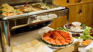 A buffet with various food items including watermelon slices, salads, and rice.