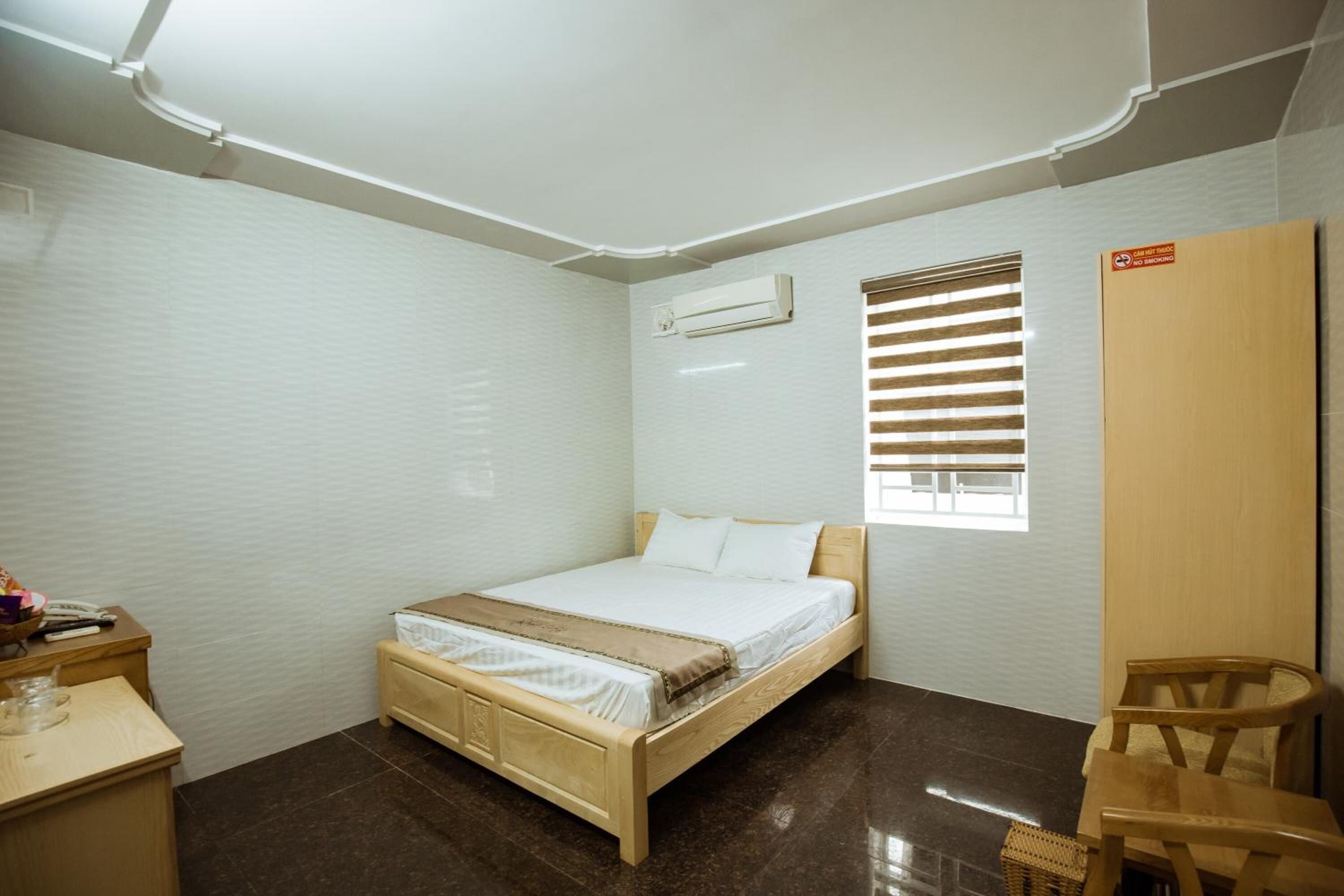 A bedroom with a wooden bed, a desk, a chair, and a wardrobe.