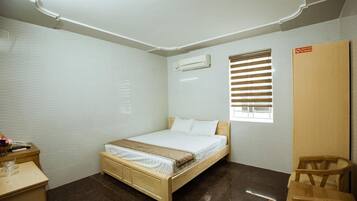 A bedroom with a wooden bed, a desk, a chair, and a wardrobe.