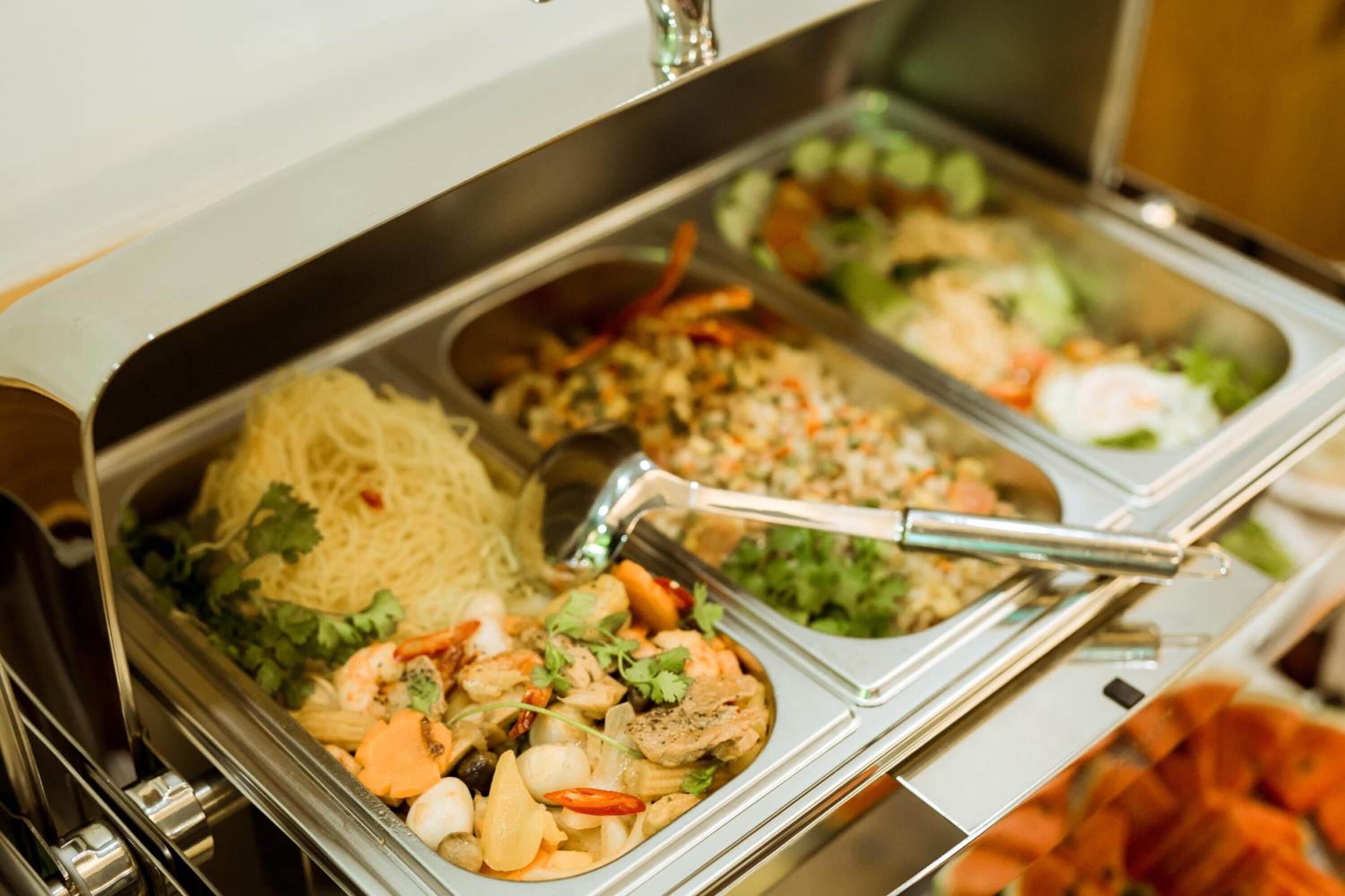 Buffet com diversos pratos, incluindo macarrão, frutos do mar e saladas.