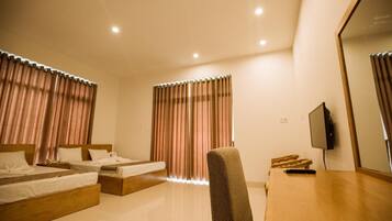 A hotel room with two beds, a desk, a chair, a TV, and curtains.
