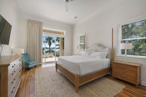 A bedroom with a large bed, wooden dresser, and a TV. - Aqua Tranquility - Waterfront with Pool in Destiny East (Destin)