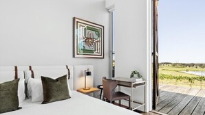 Une chambre à coucher avec un lit, un bureau et une chaise. Il y a une fenêtre donnant sur un vignoble.