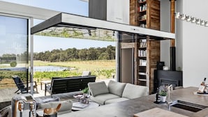 Een moderne woonkamer met een grote glazen wand, een bank, een salontafel en een open haard.
