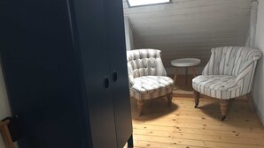 A room with a dark-colored wardrobe, two striped armchairs, a small round table, and a sloped ceiling with a skylight. - Vacation apartment B, Salzgasse, Old Town - Edition Bad Wimpfen (Bad Wimpfen)