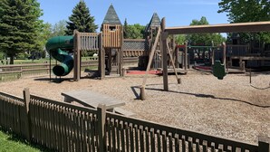 Une aire de jeux avec un toboggan, des balançoires et des structures d’escalade.