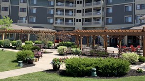 Un hôtel à plusieurs étages doté d’une cour intérieure aménagée avec des espaces de détente en plein air et de la verdure.