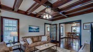 Un salon spacieux avec un canapé en cuir marron, une table basse en bois et un ventilateur de plafond.