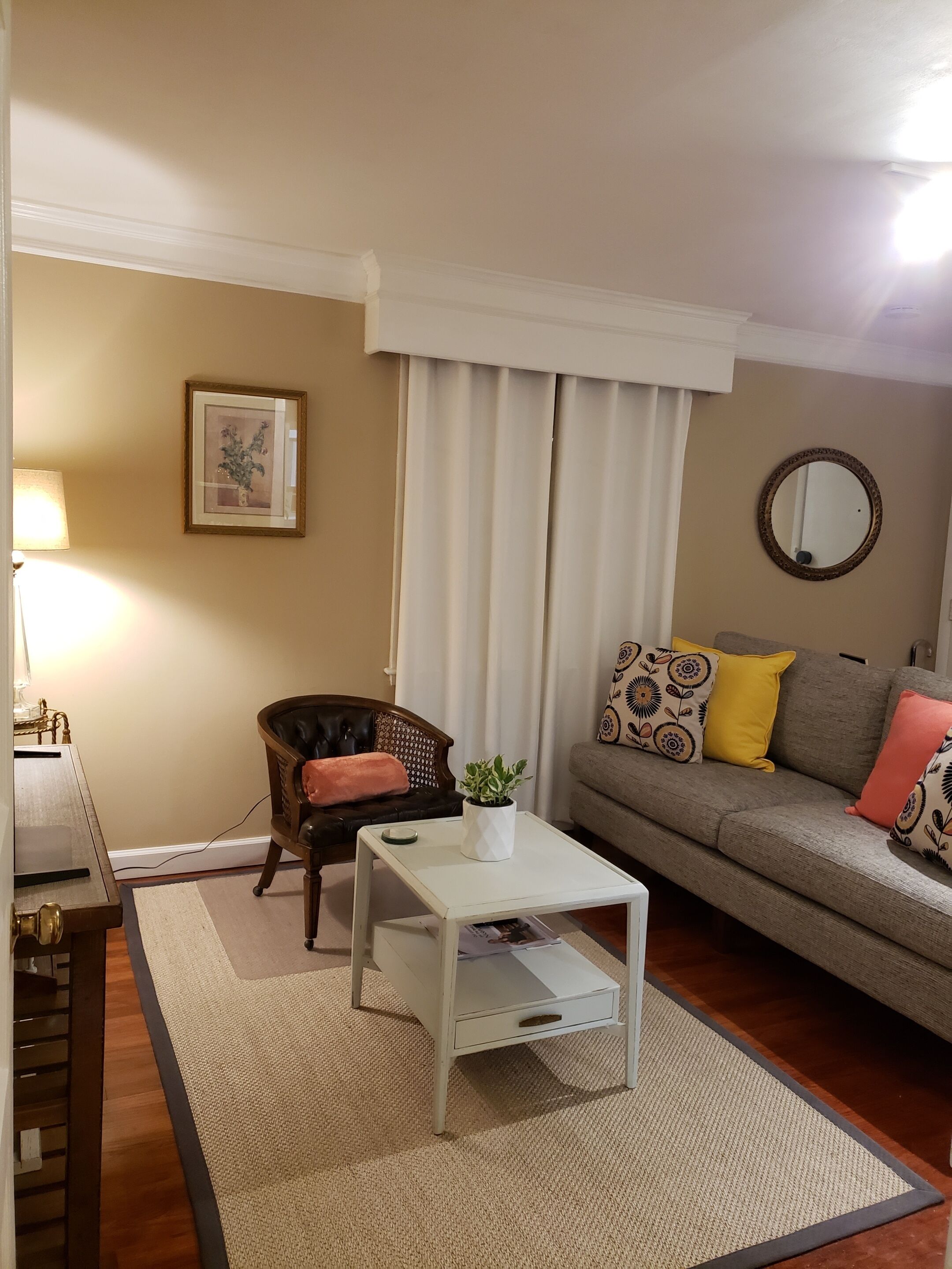 A living room with a sofa, a coffee table, a chair, a lamp, and a framed picture on the wall.