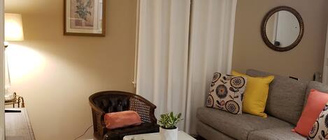 A living room with a sofa, a coffee table, a chair, a lamp, and a framed picture on the wall.
