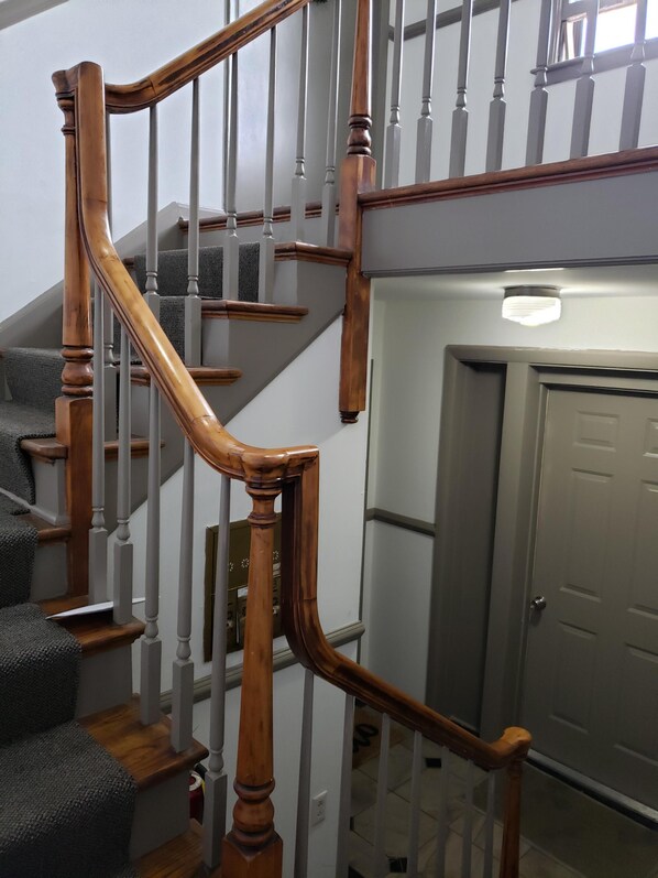 A staircase with wooden handrails and a gray carpeted landing.