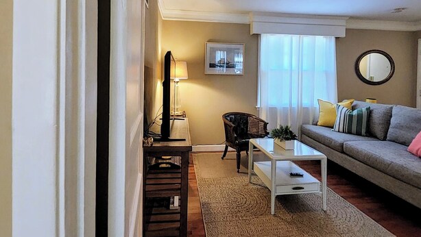A living room with a sofa, a coffee table, a lamp, a chair, and a rug. - All in Reach, 2BR in West End (Nashville)