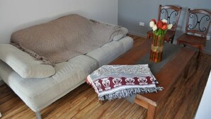 Un soggiorno con un divano, un tavolo in legno e un vaso con fiori.