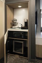 Una kitchenette compacta con cafetera, microondas y un refrigerador pequeño.