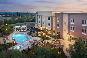 Un hotel con piscina, asientos exteriores y vistas del paisaje circundante.