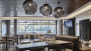 A modern dining area with hexagonal pendant lights, a large window with a view, and a flat-screen TV on the wall. - Hotel Vista Sierra (Auburn)