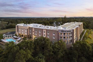 A multi-story hotel with a rooftop pool and outdoor seating area. - Hotel Vista Sierra (Auburn)