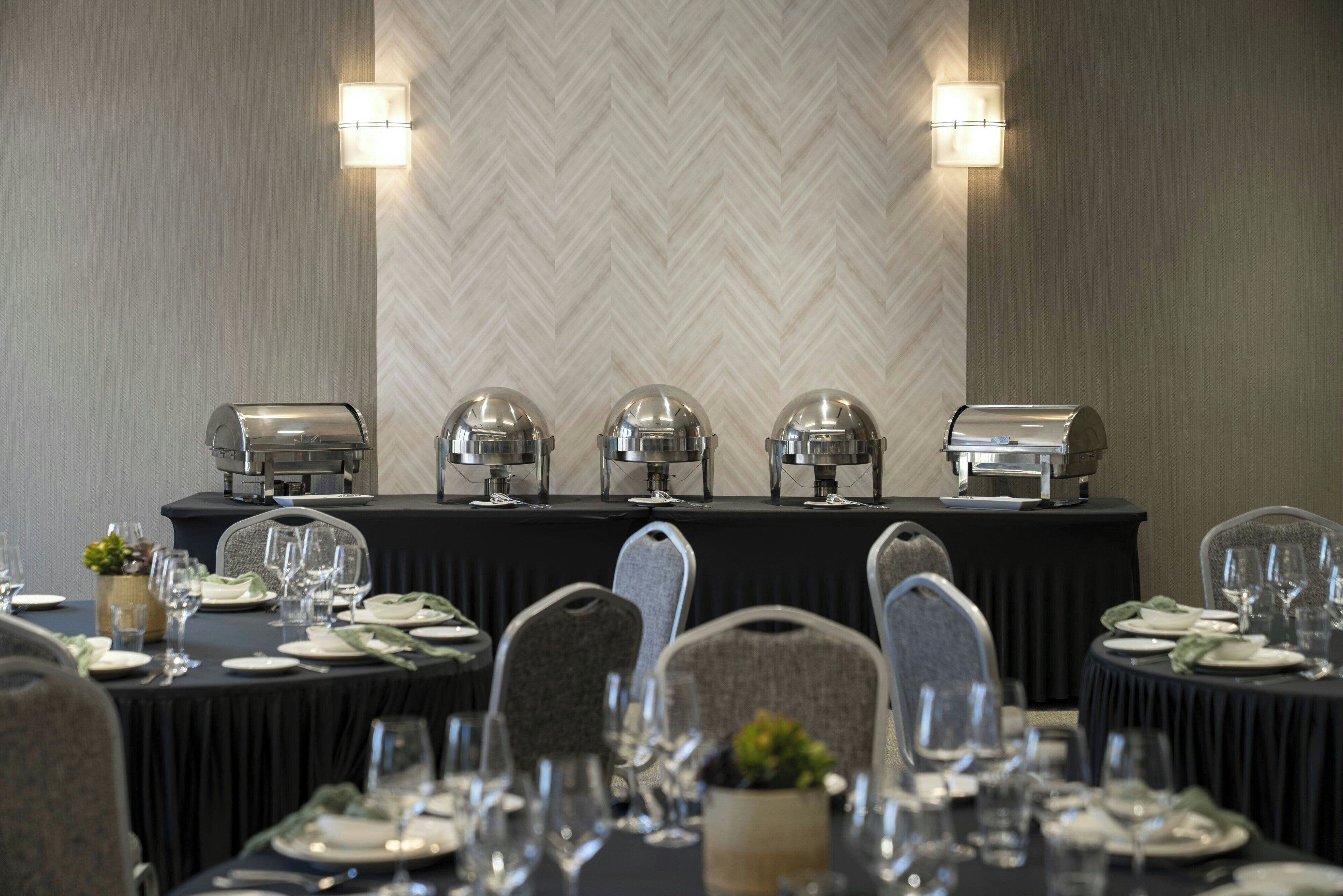 A conference room with a long table set for a meeting, equipped with a coffee station and clear glassware.
