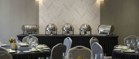 A conference room with a long table set for a meeting, equipped with a coffee station and clear glassware.