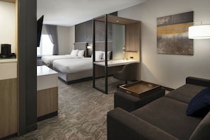 A hotel room with a bed, a desk, a sofa, and a TV. - Hotel Vista Sierra (Auburn)