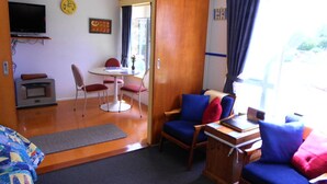 Ein Zimmer mit Esstisch, Stühlen, einem Fernseher und einer Holztür, die zu einem Außenbereich führt.