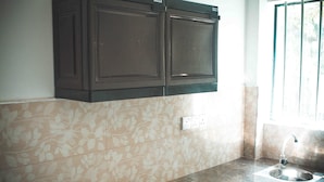 A kitchen with dark cabinets, a sink, and a window with bars. - Tanoaks Villa (Mirissa)