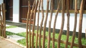 A wooden fence in front of a building with a dark brown door and windows. - Tanoaks Villa (Mirissa)