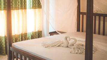 A single bed with a wooden frame and a canopy, curtains with a green and yellow pattern, and a tiled floor.
