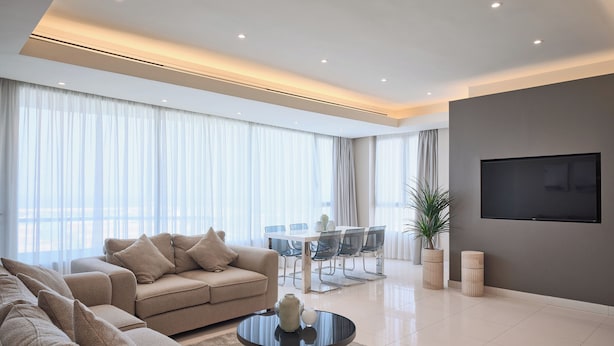 A modern living room with a sofa, coffee table, and dining area. - Code Housing - Fintas (Fintas)