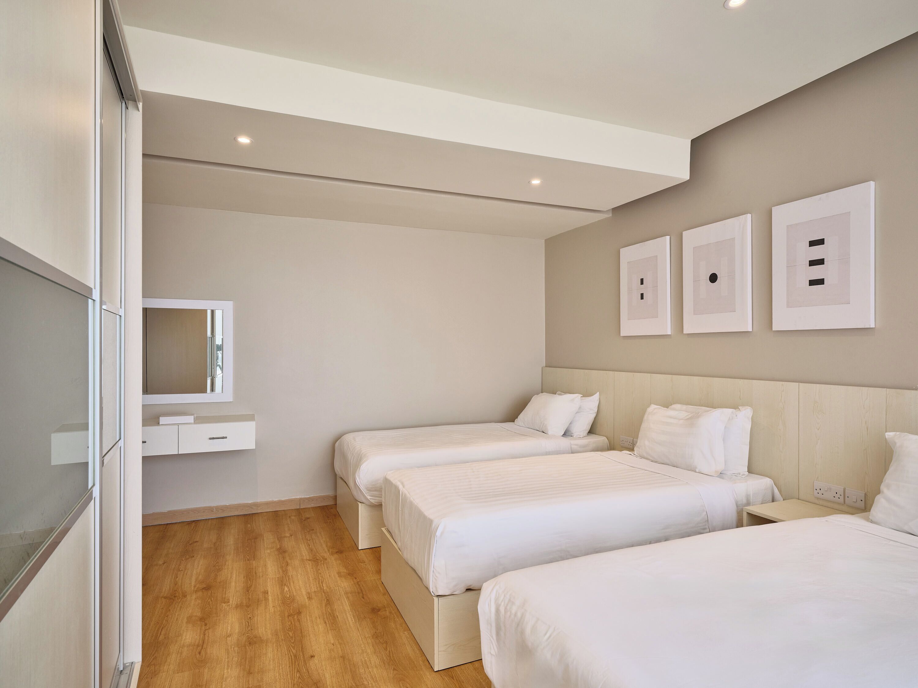 Une chambre d’hôtel avec deux lits, une table de chevet, un miroir et un luminaire fixé au mur.