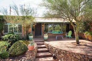 Una casa con patio, mobiliario exterior y jardín.
