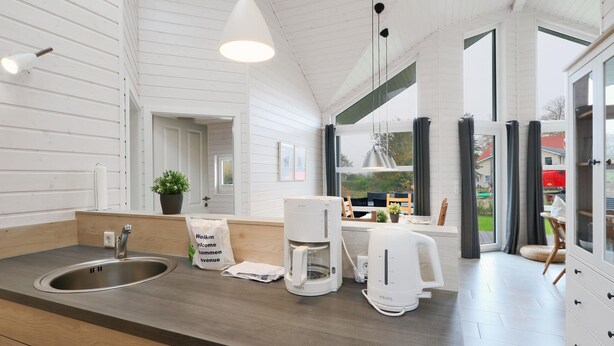 A modern kitchen with a large window, a coffee maker, and a welcome bag on the counter.