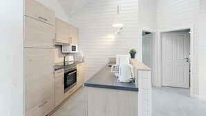 A modern kitchen with wooden cabinets, a built-in oven, a microwave, and a coffee maker.