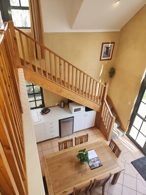 A kitchen with a wooden staircase, a dining table with chairs, and a view of the outside through a window. - Chidlow, Lake Leschenaultia, cycling & walking, Book Spa or Sauna as extra (Chidlow)