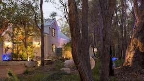 Une maison entourée d’arbres et de rochers, dont l’extérieur est bien éclairé.