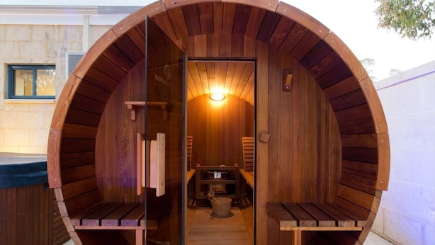 Un sauna circulaire en bois, avec un banc et une petite table à l’intérieur.