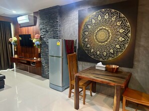 Una cuina moderna amb un frigorífic integrat, una taula de menjador de fusta i una peça decorativa a la paret.