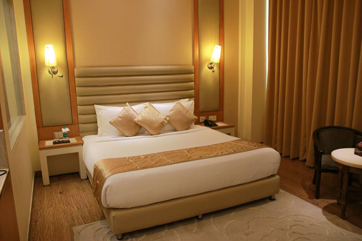 Een hotelkamer met een groot bed, nachtkastjes, een stoel en een bureau.