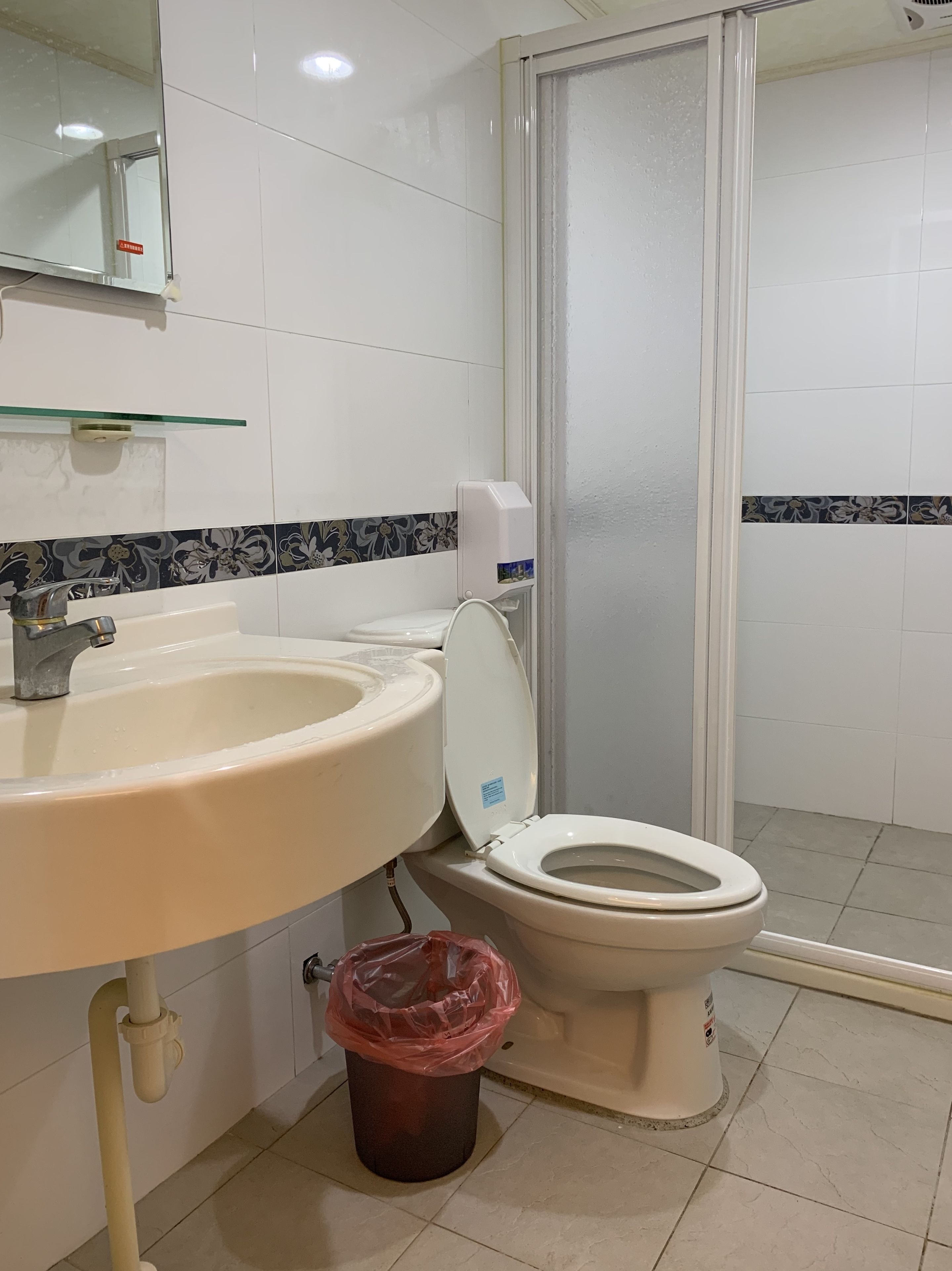 Un baño con lavamanos, inodoro y un cubo de basura.