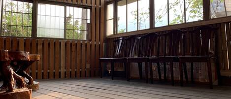 A room with wooden floors, large windows, and wooden chairs.