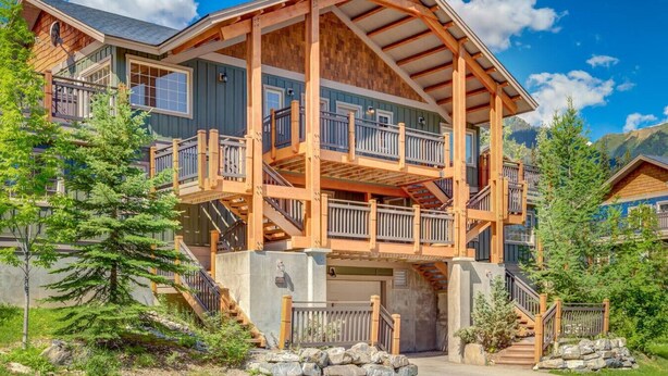 Un chalet en bois à plusieurs étages, doté de balcons et d’un garage.