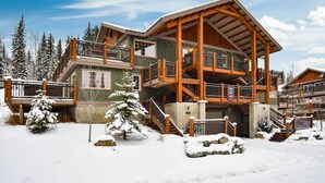 Un chalet à étages doté de balcons en bois, situé dans un paysage enneigé.