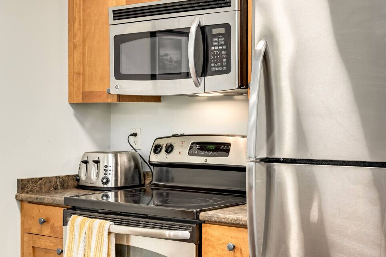 Una cocina equipada con microondas, tostadora, estufa y refrigerador.
