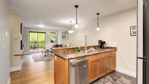 Une cuisine moderne dotée d’un îlot central en bois, d’appareils électroménagers en acier inoxydable et de luminaires suspendus.