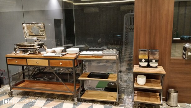 Una habitación de hotel con un escritorio de madera, un espejo y una estantería con cuencos y una cafetera.