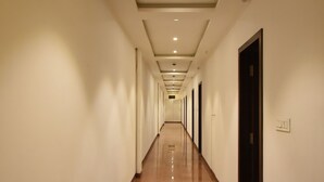 Un largo y estrecho pasillo de hotel con piso pulido e iluminación empotrada en el techo.