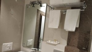 Un baño moderno con un espejo grande, un lavabo blanco y un perchero para toallas.