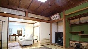 A traditional Japanese room with tatami flooring, a low wooden table, a sofa, and a sliding door leading to another room. - 4A House for Family with tatami (大阪市浪速区大国3-4-6)